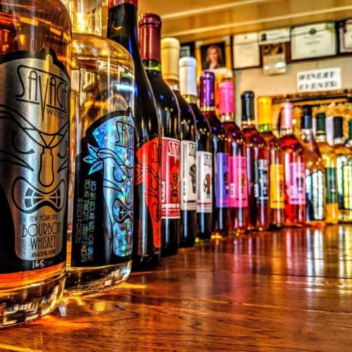 A colorful display of various whiskey and wine bottles arranged on a wooden surface.