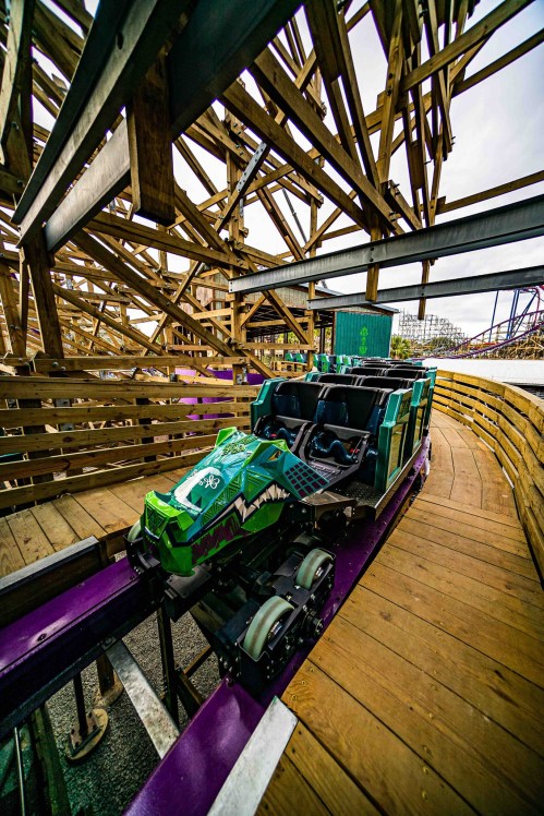 A colorful roller coaster car on a wooden track, surrounded by the structure of the ride.
