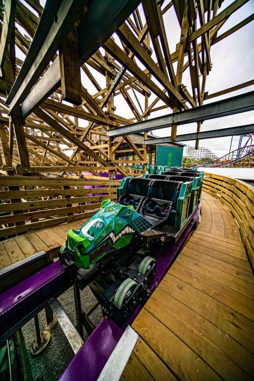 A colorful roller coaster car on a wooden track, surrounded by the structure of the ride.