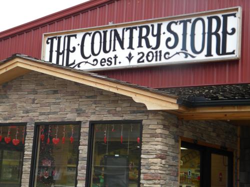Sign for "The Country Store" with a stone facade, established in 2011, featuring heart decorations in the windows.