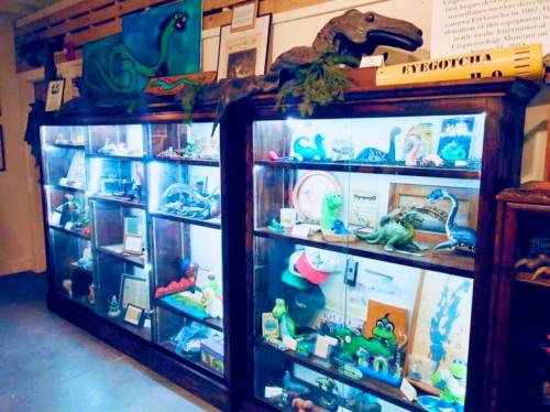 Display cases filled with various dinosaur models, artifacts, and colorful decorations in a museum setting.