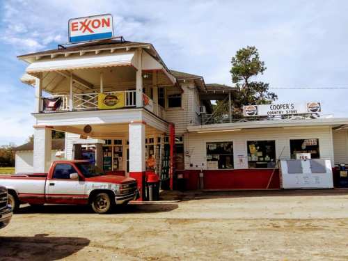 A vintage Exxon gas station with a country store, featuring a red pickup truck parked outside.