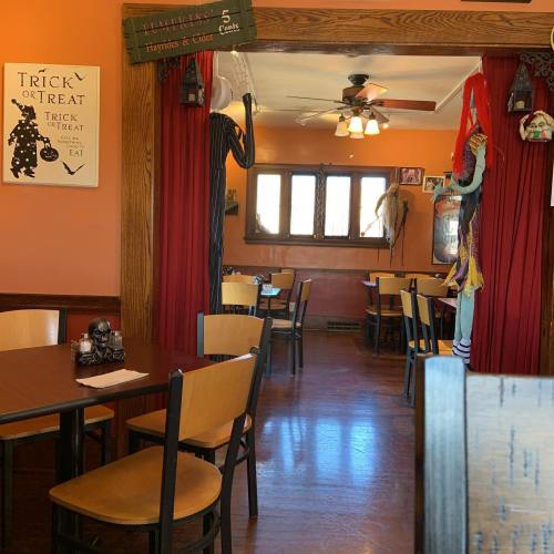 A cozy restaurant decorated for Halloween, featuring spooky decor and empty tables.
