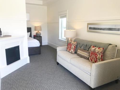 Cozy room featuring a sofa with decorative pillows, a bed, and a fireplace in a bright, minimalist setting.