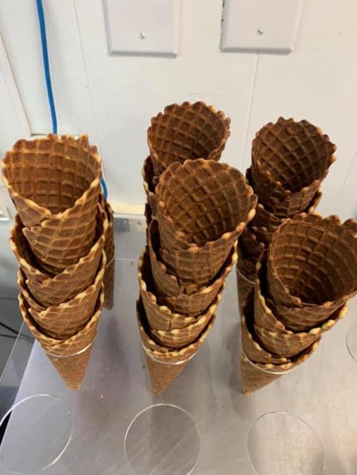 A stack of empty waffle ice cream cones arranged neatly on a countertop.