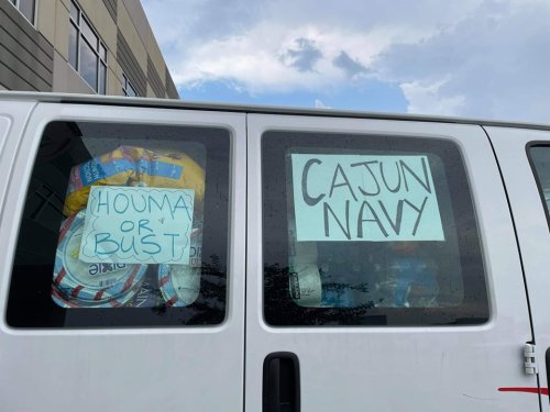 A van window displays signs reading "Houma or Bust" and "Cajun Navy," with colorful supplies visible inside.