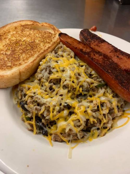 A plate of cheesy beef and rice casserole with toast and sausage links on the side.