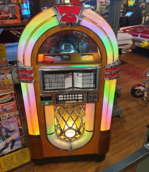 A vintage jukebox with colorful lights, displaying music selection options in a retro setting.