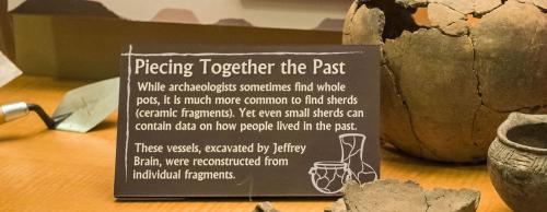 Sign about archaeological findings, discussing the importance of pottery shards and reconstruction of vessels by Jeffrey Brain.