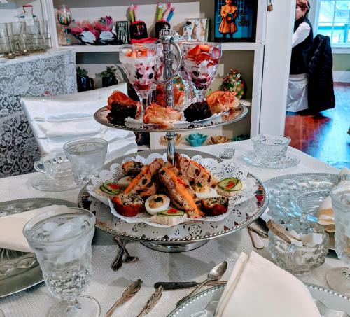 A tiered dessert stand with assorted pastries, sushi, and fruit parfaits, set on an elegantly arranged table.