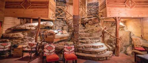 Cozy interior of a rustic cabin featuring stone stairs, wooden accents, and comfortable seating.