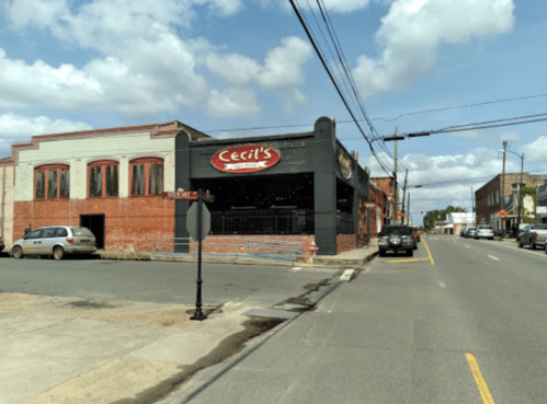 A street view of Cecil's restaurant with a brick building and parked cars under a cloudy sky.