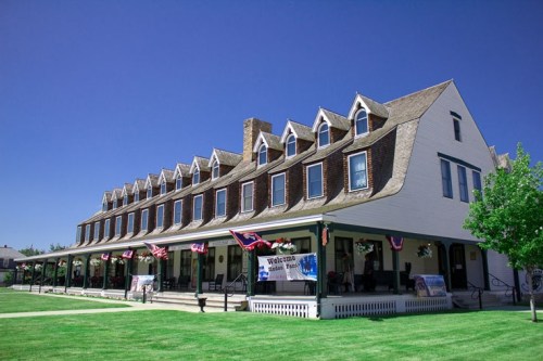 Historic building with multiple gabled roofs, green lawn, and banners, under a clear blue sky.