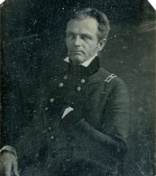 A historical portrait of a man in a military uniform, seated with a serious expression.