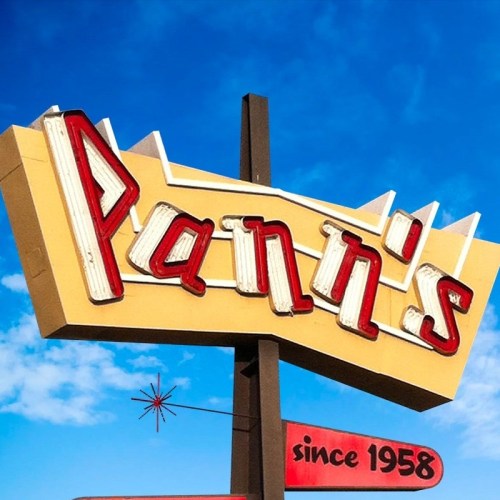 Sign for Pann's restaurant, featuring retro lettering and a starburst design, with a clear blue sky in the background.