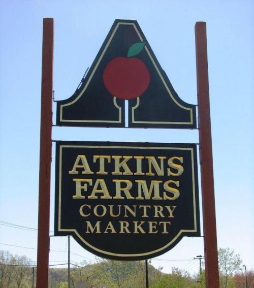 Sign for Atkins Farms Country Market featuring a red apple logo and bold text on a black background.