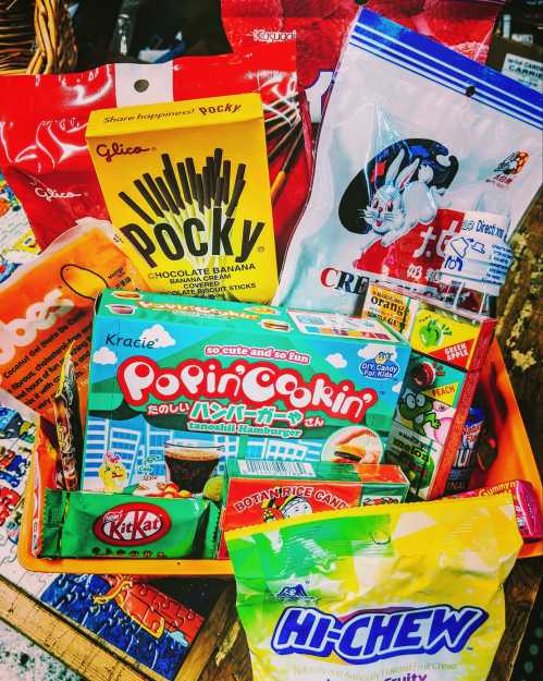 A colorful assortment of Japanese snacks, including Pocky, Hi-Chew, and Popin' Cookin', arranged in a basket.