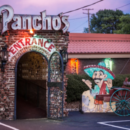 Entrance to Pancho's restaurant, featuring a brick archway and a colorful mural of a smiling sombrero-wearing character.