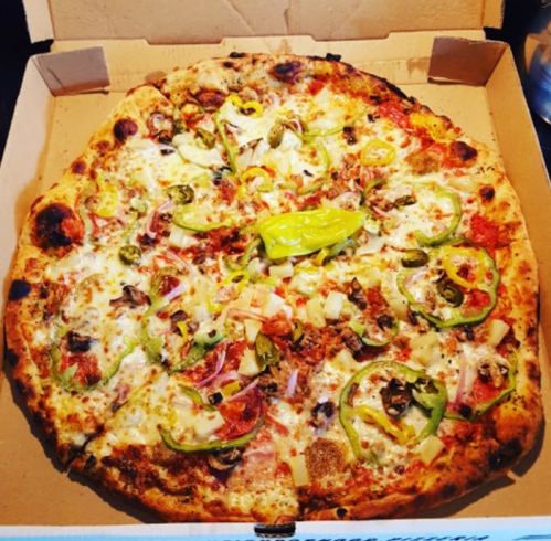 A large pizza topped with pepperoni, green peppers, mushrooms, onions, and jalapeños in a pizza box.