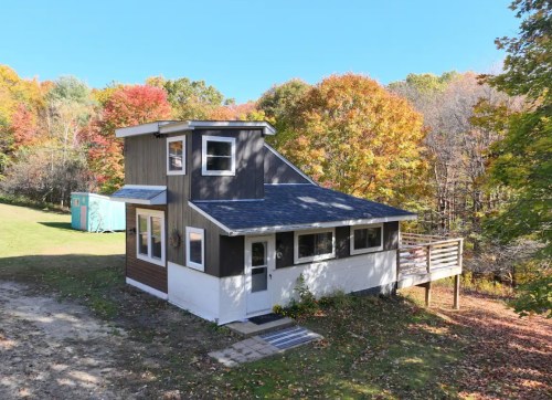 A modern two-story house surrounded by colorful autumn trees and a grassy area.
