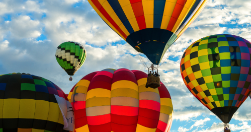 Colorful air balloons take off, and a basket with a people inside are visible.