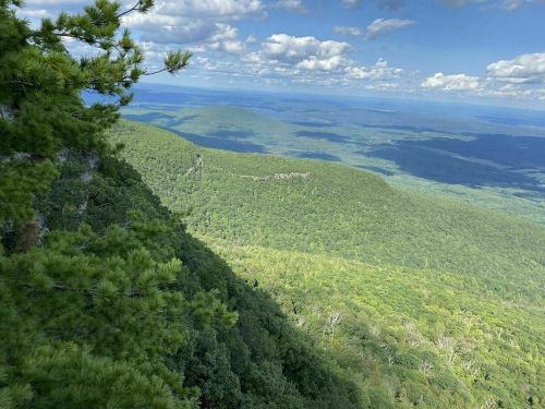 A panoramic view of lush green mountains under a blue sky with scattered clouds.