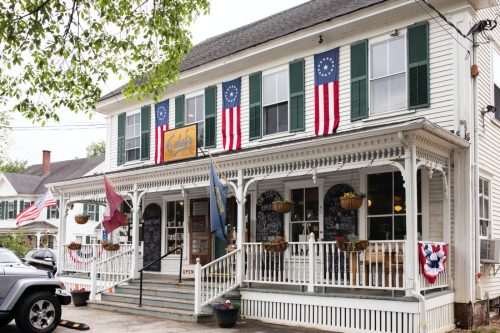 A charming storefront with green shutters, flags, and a welcoming porch, featuring a sign that reads "Galati's."