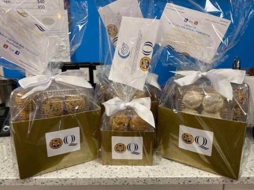Three gift boxes filled with assorted cookies, wrapped in clear cellophane and tied with white ribbons.