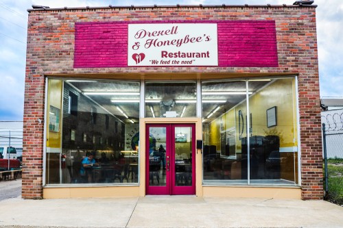 Exterior of Drexell & Honeybee's Restaurant, featuring a pink sign and large windows, inviting diners inside.