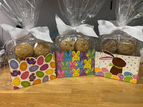 Three gift bags with cookies, decorated with colorful Easter-themed designs and tied with white ribbons.