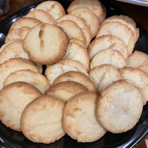 A plate of freshly baked, golden-brown cookies arranged in a circular pattern.
