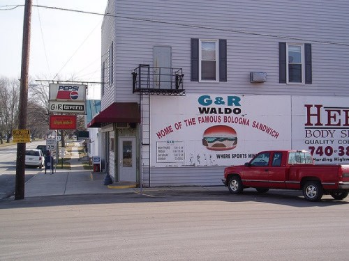 Exterior view of G&R Tavern, featuring a sign for the famous bologna sandwich and a red pickup truck parked outside.