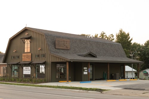 A modern barn-style building with a wooden exterior and large windows, featuring a sign that reads "gloz."