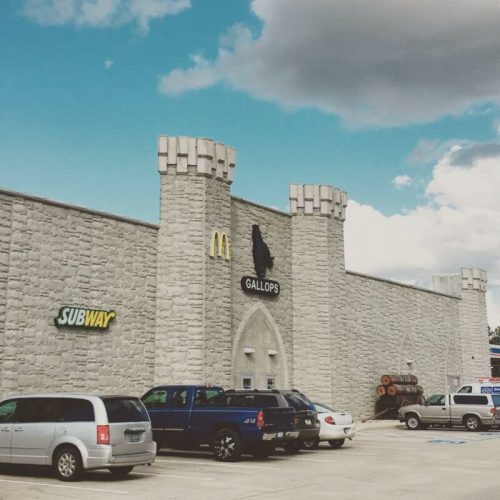 A building featuring a Subway and McDonald's, with a castle-like design and blue sky in the background.