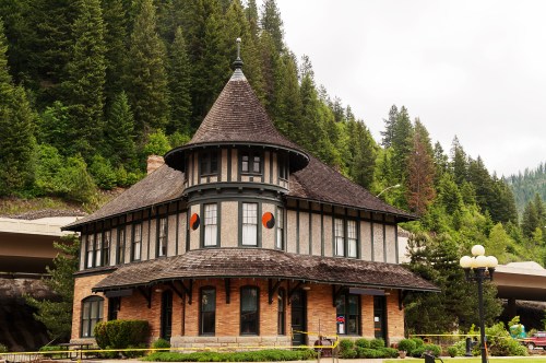 Historic building with a conical roof, surrounded by trees and a highway, showcasing unique architectural details.