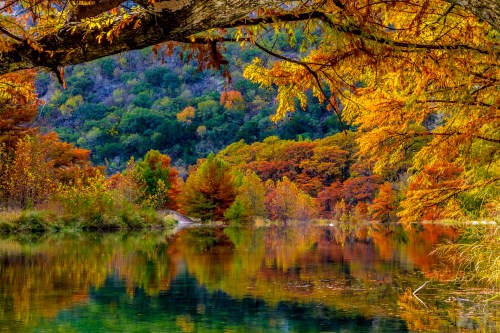 A serene river surrounded by vibrant autumn foliage reflecting on the water's surface.