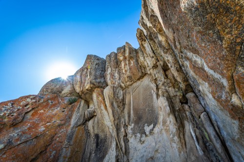 Sunlight shines over rugged rock formations against a clear blue sky.