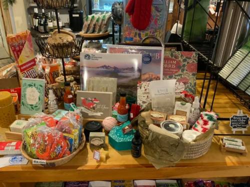 A display of various gift items, including snacks, candles, and decorative products, arranged on a wooden table.