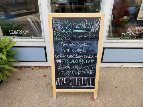 Chalkboard sign listing cupcake flavors: Strawberry, White Blueberry, Wedding Cake, Dutch Chocolate. Buy 5, get 1 free.