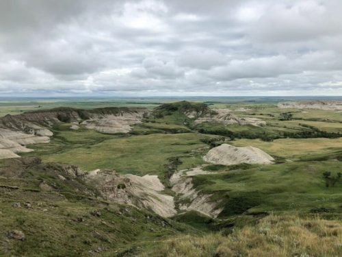 A panoramic view of rolling hills and grassy plains under a cloudy sky.
