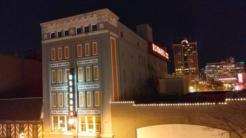 A nighttime view of a building with illuminated windows and a sign reading "Levy's Place" in a cityscape.