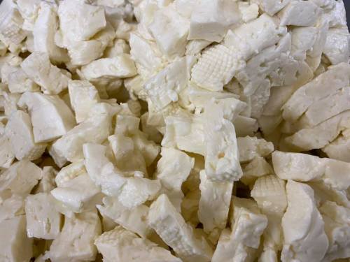 Close-up of chopped white cheese pieces, with a textured surface, piled together in a dish.