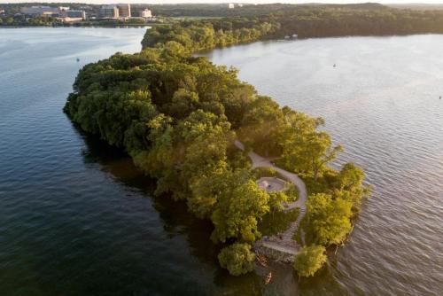 Aerial view of a lush, green island surrounded by calm water, featuring a winding path and trees.