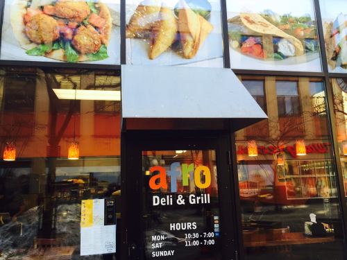 Exterior view of Afro Deli & Grill, featuring a menu display and hours of operation on the door.