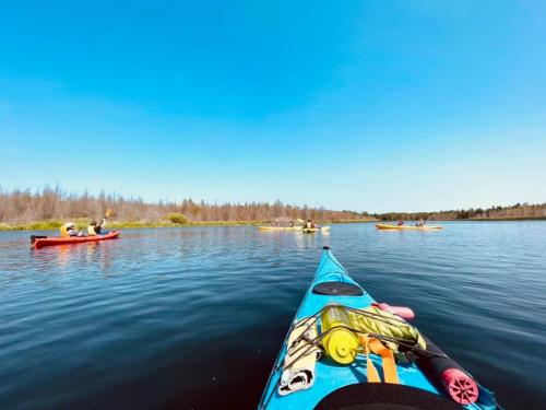A view from a kayak on calm water, with other kayakers in the distance under a clear blue sky.