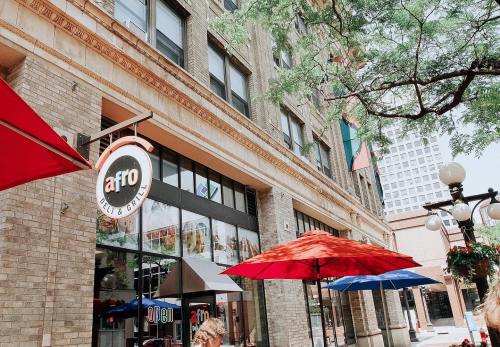 Exterior of a restaurant with a sign reading "Afro," featuring colorful umbrellas and a brick building.