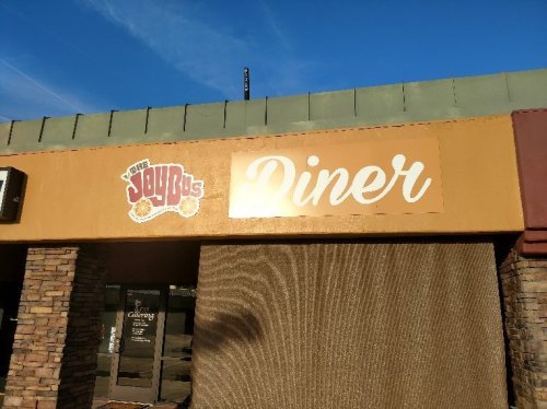Sign for "Joy's Diner" on a building exterior, featuring a colorful logo and a warm, inviting design.