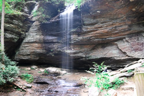A serene waterfall cascading over rocky cliffs, surrounded by lush greenery and a tranquil stream below.