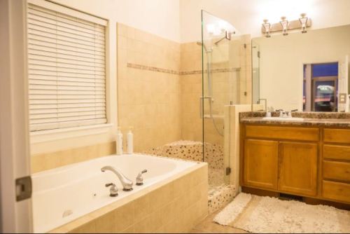 A modern bathroom featuring a glass shower, a bathtub, wooden cabinetry, and a large mirror.