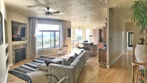 Spacious living room with a large window, modern furniture, and a view of the outdoors. Light wood floors and a cozy atmosphere.